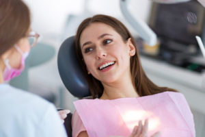Lady sitting in a dental chair speeking with a dentist.