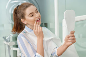 Dental patient observing her new smile in a mirror.